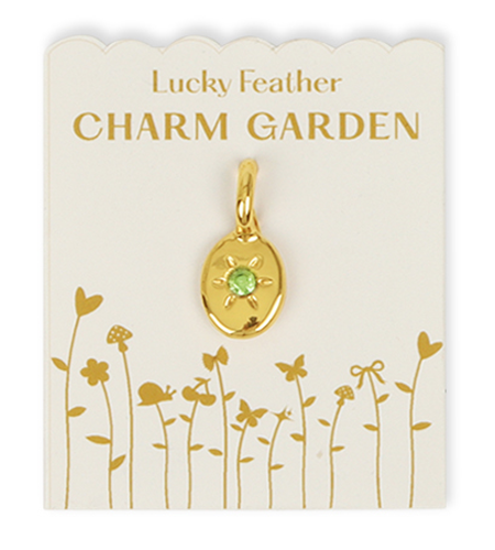 A gold charm with a green stone is displayed on a 'Lucky Feather CHARM GARDEN' card.