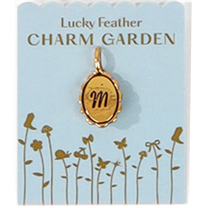 A gold charm pendant with the letter 'm' on a blue card with a garden illustration and the words 'Lucky Feather CHARM GARDEN'.
