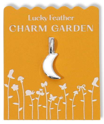 A silver crescent moon charm on a yellow card with a floral design.