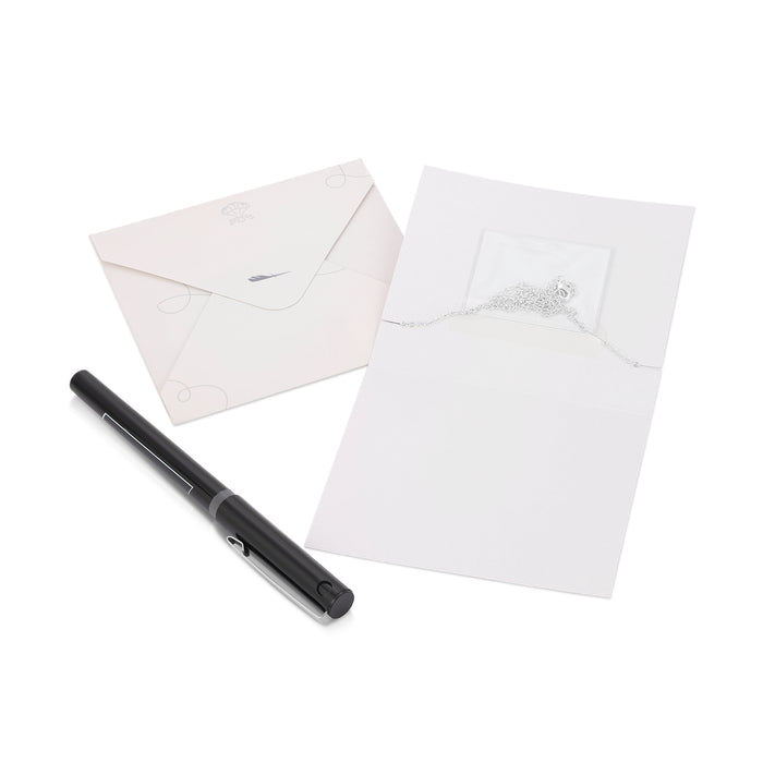 The image shows two envelopes, a necklace partially visible in one, and a black pen on a white surface.