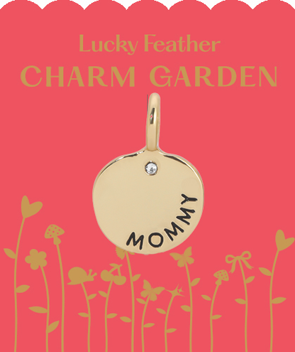 A golden 'Mommy' charm on a pink 'Lucky Feather Charm Garden' card with a floral and butterfly design.