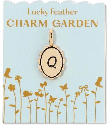 A gold-colored charm with the letter 'Q' hangs from a blue card that reads 'Lucky Feather CHARM GARDEN' and features illustrations of flora and fauna.