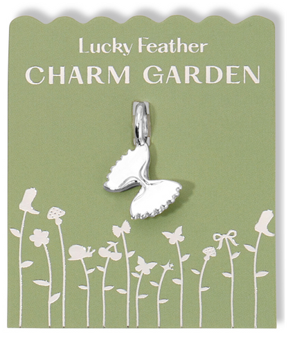A silver butterfly charm on a green card with white garden-themed graphics and the words 'Lucky Feather CHARM GARDEN'.