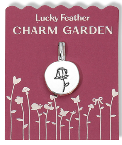 A Lucky Feather 'Charm Garden' pendant with a rose design on a card with a garden illustration.