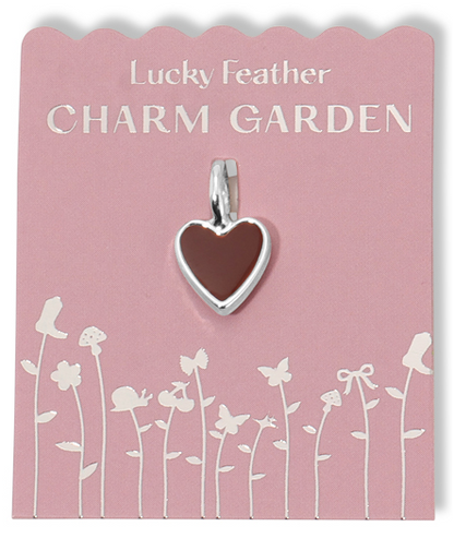 A heart-shaped charm is displayed on a pink card with silver text and floral designs.
