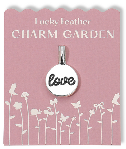 Love charm on a pink 'Lucky Feather Charm Garden' display card with flower graphics.