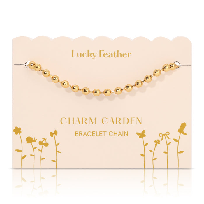 A gold bead bracelet chain on a decorative 'Lucky Feather Charm Garden' display card.