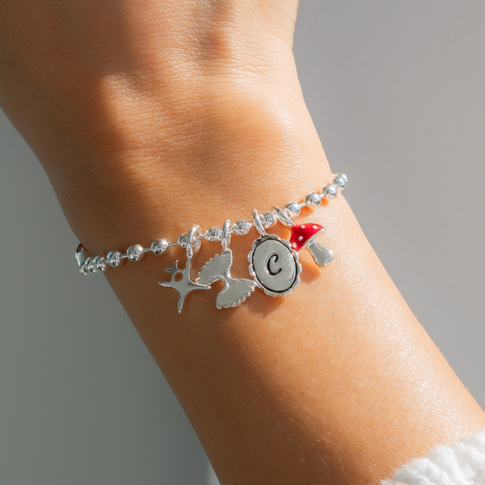 A wrist wears a silver charm bracelet.