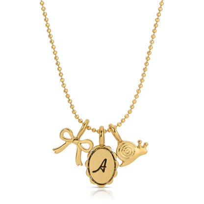 A gold ball-chain necklace features charms of a bow, an 'A' initial pendant, and a snail.