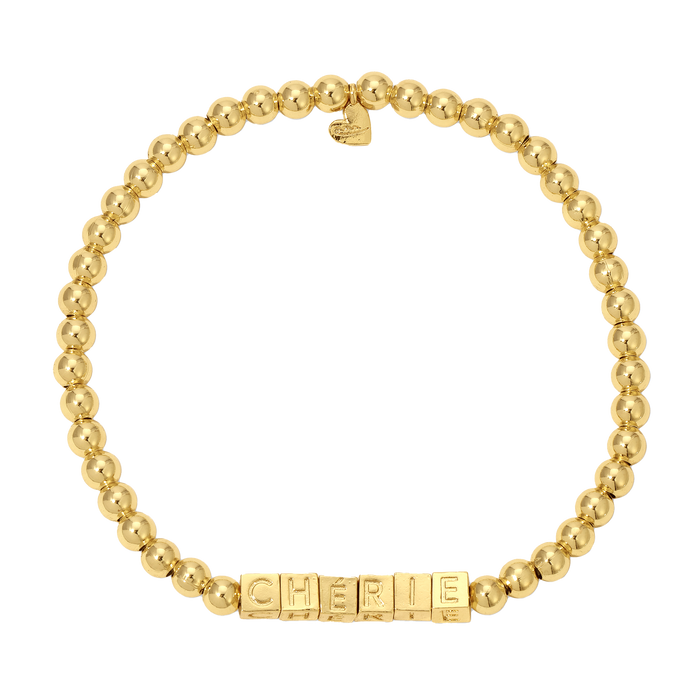 A gold bead bracelet with the word 'CH√âRIE' spelled out in square letter beads.