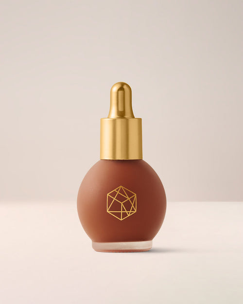 EM Cosmetics Color Drops Serum Blush in Autumn Sky, a muted coral liquid blush for a warm, healthy-looking dewy flush.