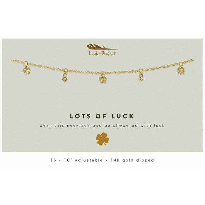 A gold-colored necklace with clover and jewel charms is displayed on a card that reads 'Lots of Luck'.