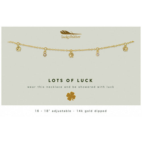 A gold-colored necklace with clover and jewel charms is displayed on a card that reads 'Lots of Luck'.
