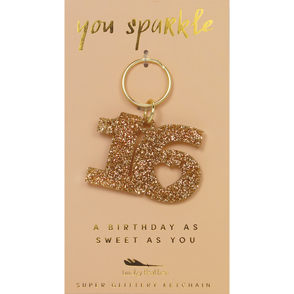 A glittery number 16 keychain hangs on a card that reads 'you sparkle' and 'a birthday as sweet as you.'