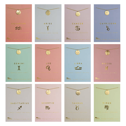 Twelve gold zodiac necklaces are displayed on individual cards.