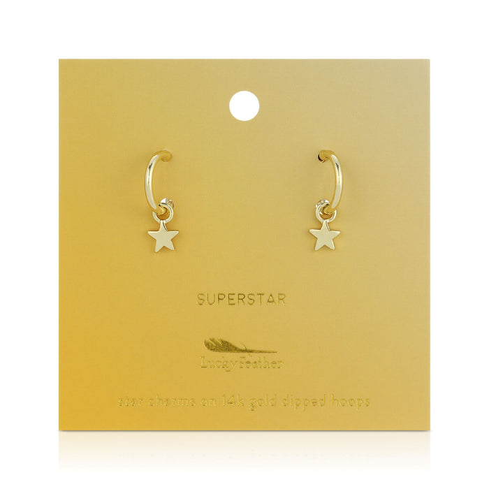 Two gold hoop earrings with star charms are displayed on a gold-colored card.