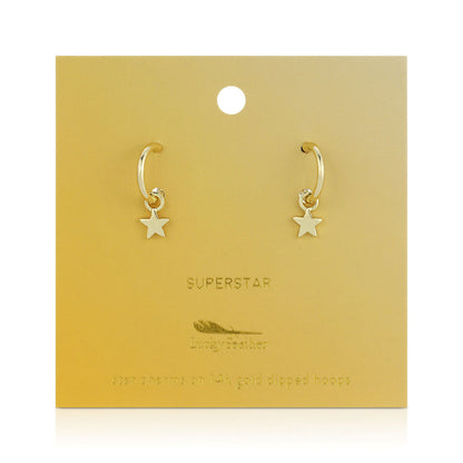 Two gold hoop earrings with star charms are displayed on a gold-colored card.