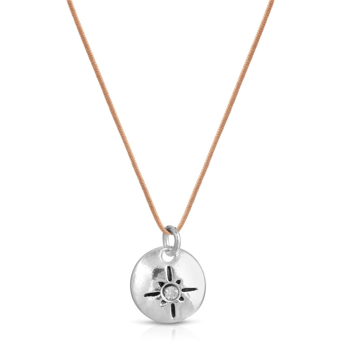 A necklace with a silver disc pendant featuring a sun or starburst design on a tan cord.