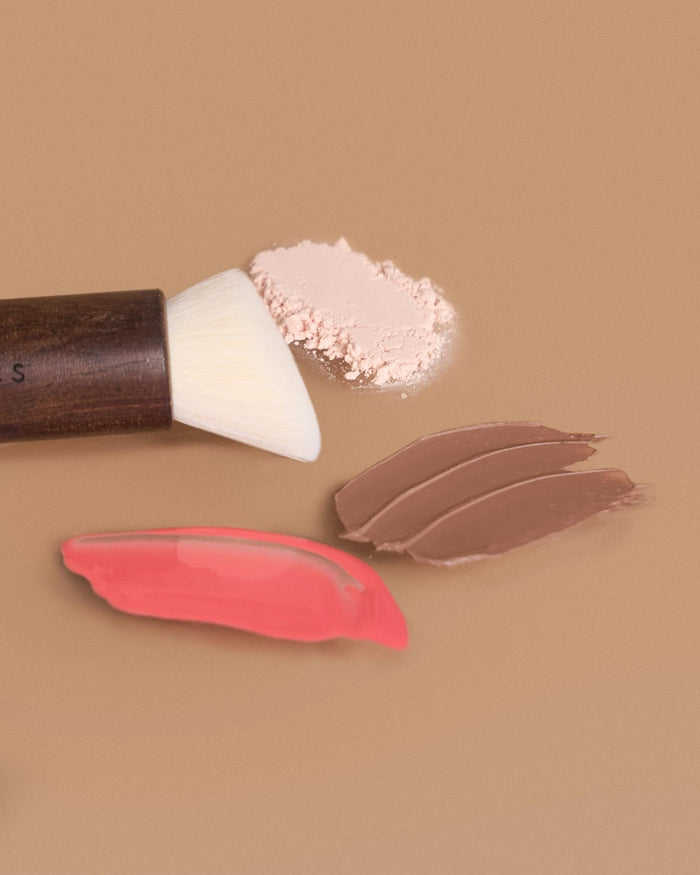 A lifestyle shot of the EM Cosmetics Komorebi Brush, a versatile tool for sculpting and adding a flush of color.