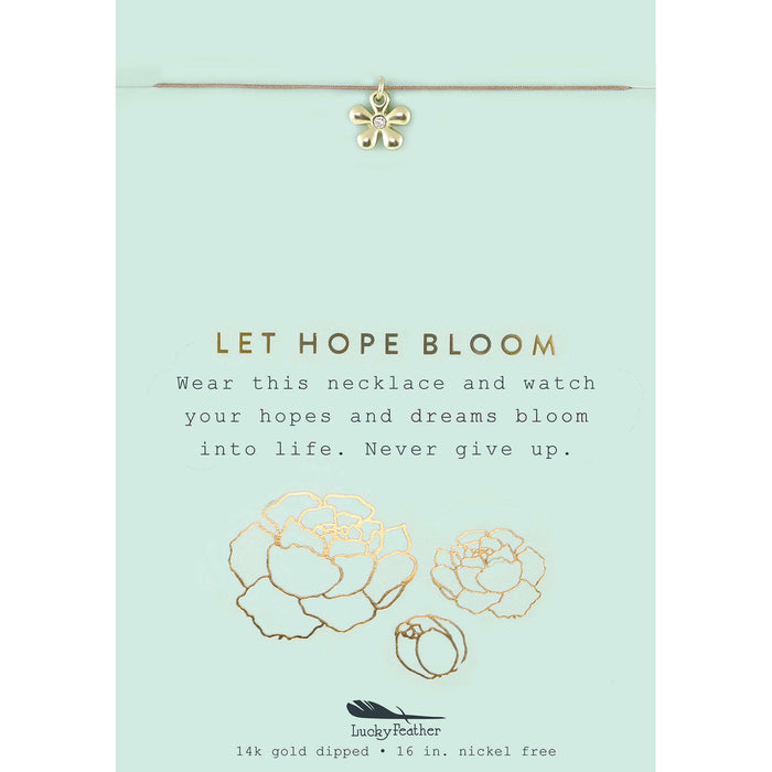 A gold flower pendant hangs from a necklace on a card that reads 'LET HOPE BLOOM.'