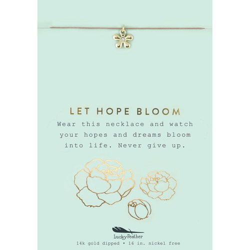 A gold flower pendant hangs from a necklace on a card that reads 'LET HOPE BLOOM.'