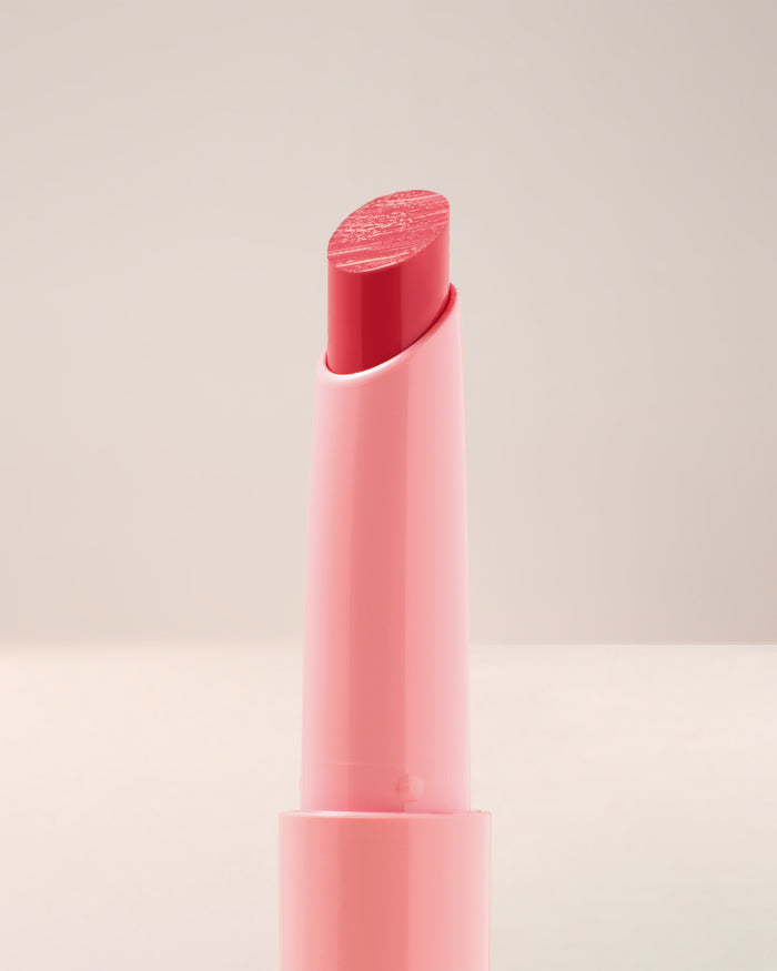 Model with light skin wearing EM Cosmetics Lip Cushion in Angèle for a comfortable, luminous, and cushiony finish.