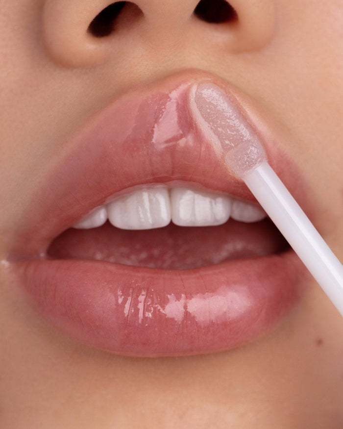 Model with light-medium skin wearing EM Cosmetics Crystal Lip Gloss for a high-shine, plump, and hydrated pout.