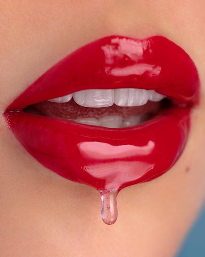 Model with light-medium skin shows the wet-look finish of EM Cosmetics Morning Dew Crystal Lip Gloss in Quartz.