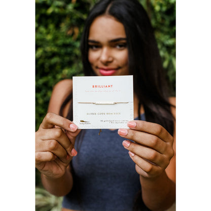 A woman holds up a Lucky Feather 'Brilliant' Morse code bracelet.