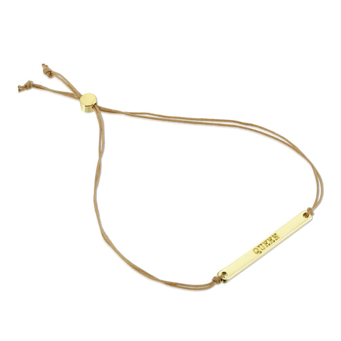 A gold-colored bracelet with the word 'QUEEN' engraved on it, attached to a light brown cord.