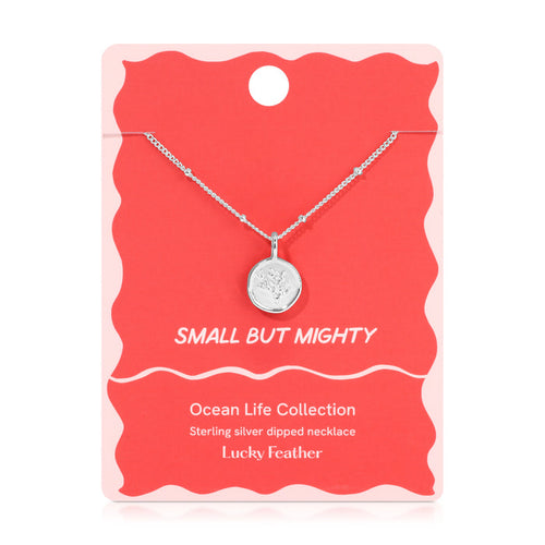 A silver necklace with a round pendant featuring a feather design, displayed on a red and pink card that reads 'SMALL BUT MIGHTY' and 'Lucky Feather'.