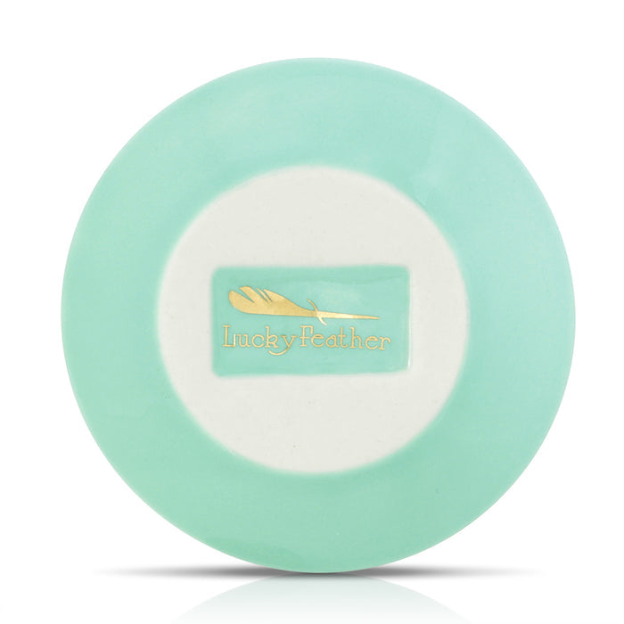 Overhead shot of a round, light turquoise dish with a white center displaying the 'Lucky Feather' logo.