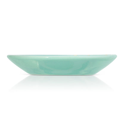 A turquoise bowl is centered on a white background with a reflection.