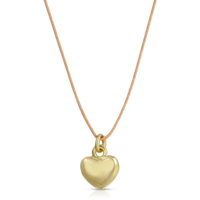 A gold heart pendant necklace hangs on a tan cord.