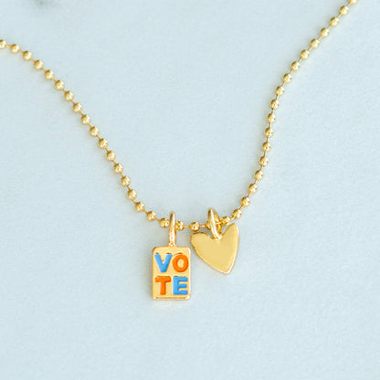 A gold ball chain necklace features 'VOTE' and heart charms.