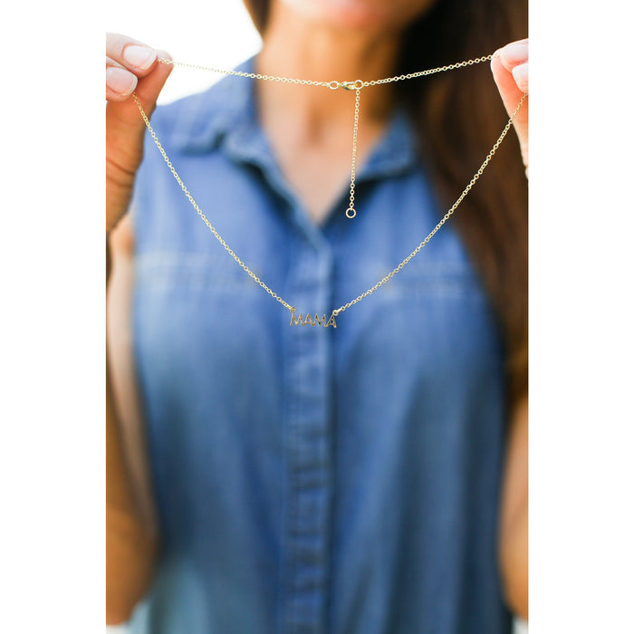 A person holding a gold necklace with the word 'MAMA'.