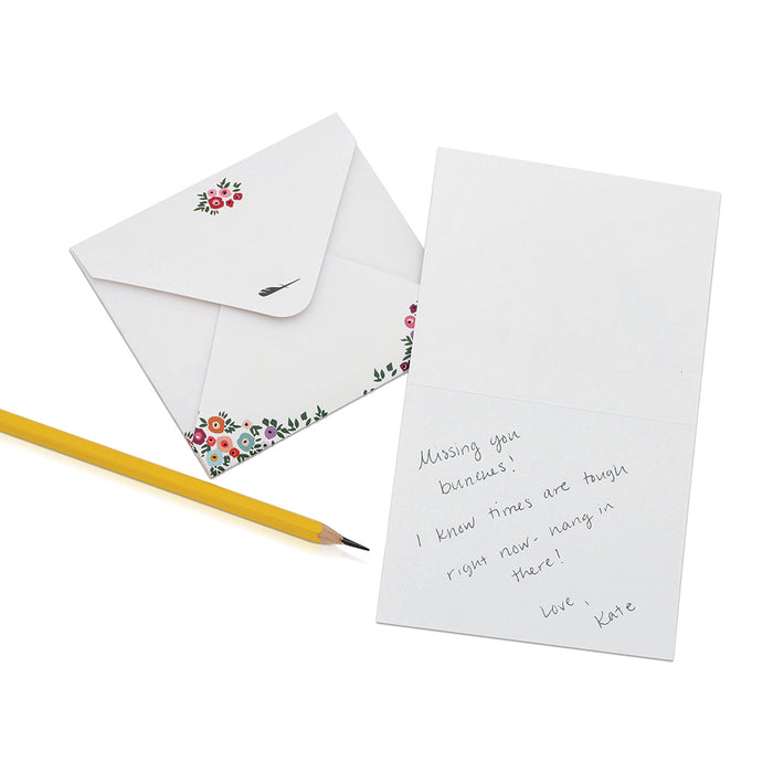 A floral-decorated envelope and handwritten note lay next to a yellow pencil.