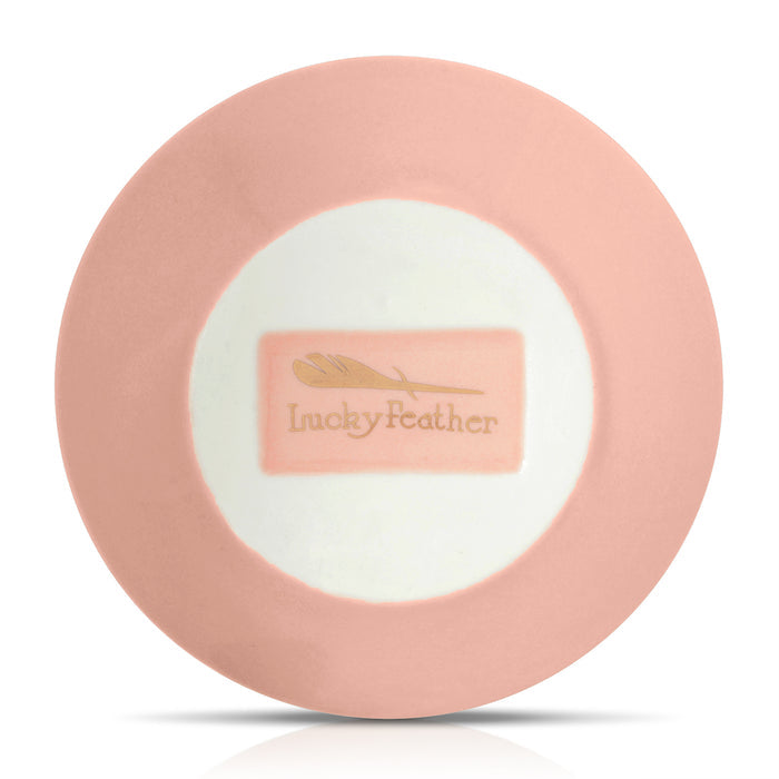 A circular plate with a pink rim and a white center featuring the text 'Lucky Feather' in a rectangular design.